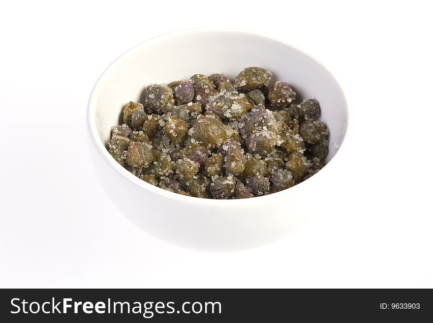 Capers preserved in sea salt in a bowl on white background. Capers preserved in sea salt in a bowl on white background