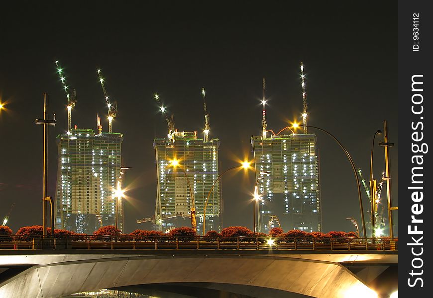 Buildings under construction with a number of cranes at night. Buildings under construction with a number of cranes at night.