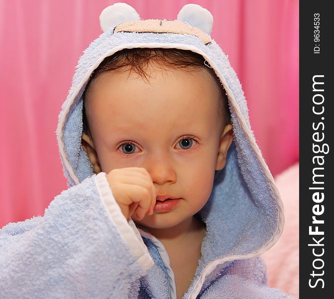 Little boy sitting on a bed after bath, dressed in blue bathrobe, portrait,. Little boy sitting on a bed after bath, dressed in blue bathrobe, portrait,