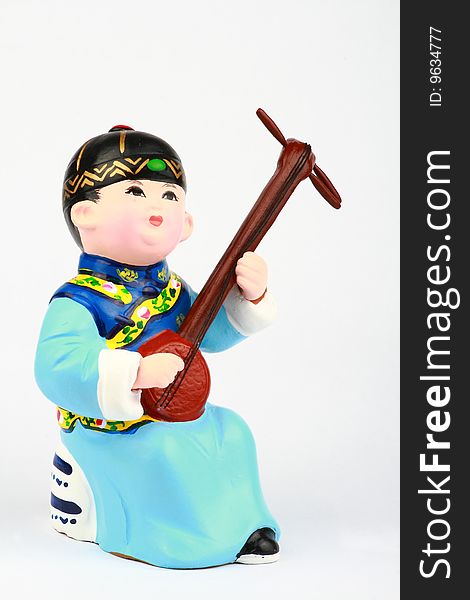 This is a clay figure of an Asian boy in traditional robe playing a stringed instrument. This is a clay figure of an Asian boy in traditional robe playing a stringed instrument.