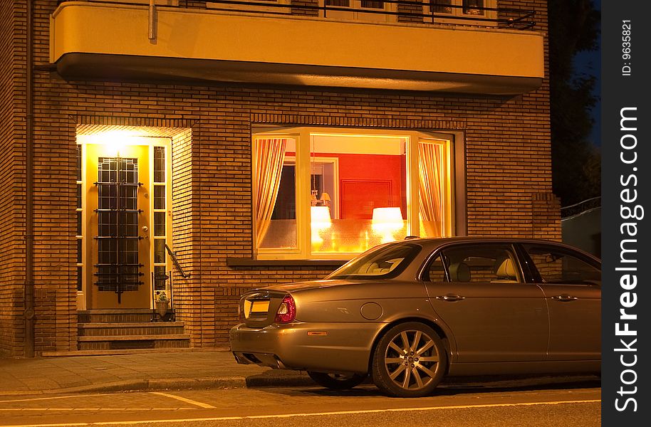 A Jaguar car parked in front of a house at night after a long day of work. A Jaguar car parked in front of a house at night after a long day of work