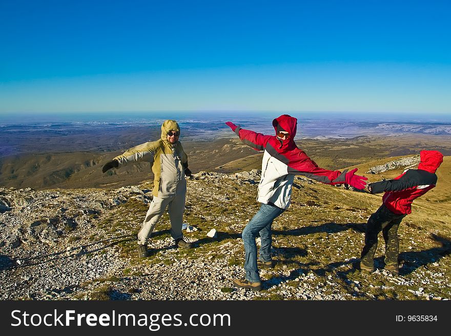 Happy hikers wave their hands and playing with strong wind on mountain summit. Happy hikers wave their hands and playing with strong wind on mountain summit