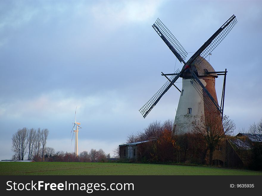 Morning light, traditional windmill in the foreground and modern windmill generators on a background. Morning light, traditional windmill in the foreground and modern windmill generators on a background