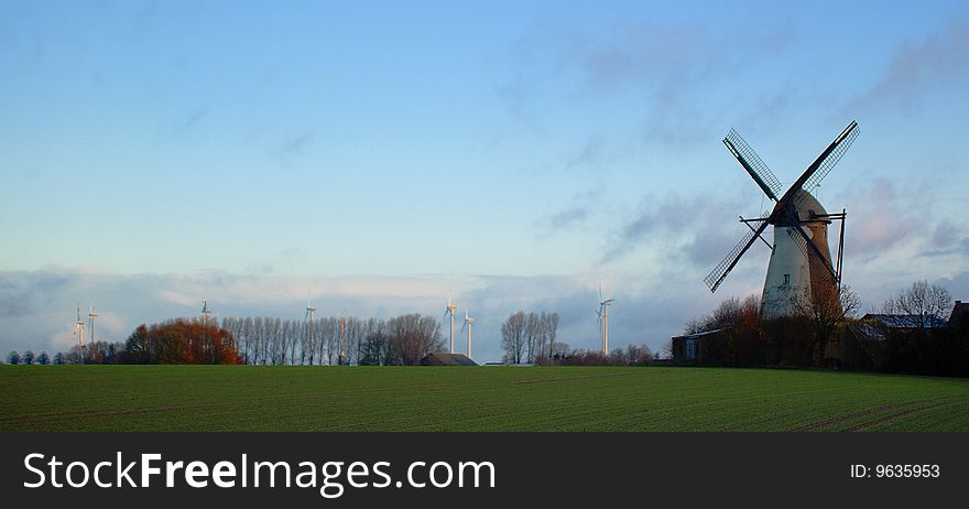 Morning light, traditional windmill in the foreground and modern windmill generators on a background. Morning light, traditional windmill in the foreground and modern windmill generators on a background