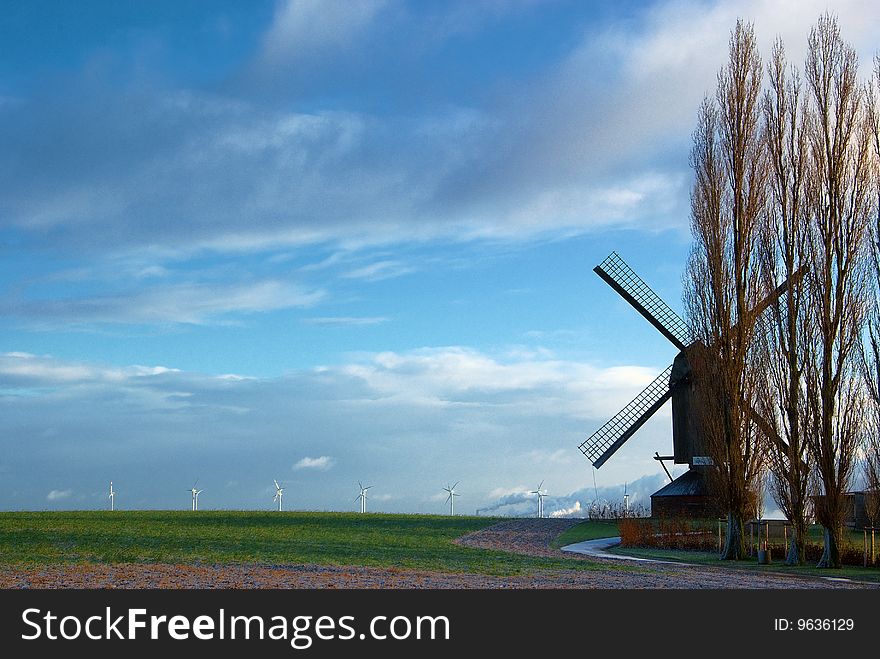 Traditional windmill in the foreground and modern windmill generators on a background. Traditional windmill in the foreground and modern windmill generators on a background