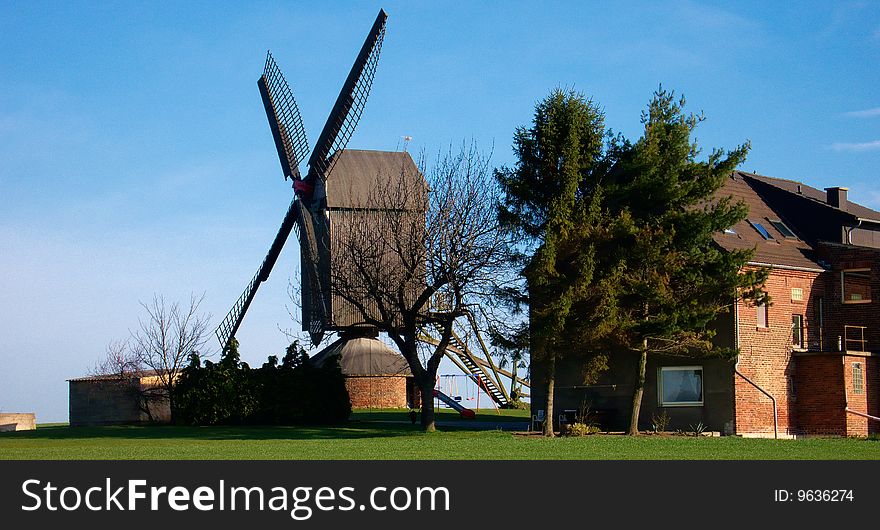 Morning light, traditional windmill and house, green grass and blue sky