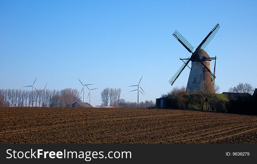 Morning light, traditional windmill in the foreground and modern windmill generators on a background. Morning light, traditional windmill in the foreground and modern windmill generators on a background