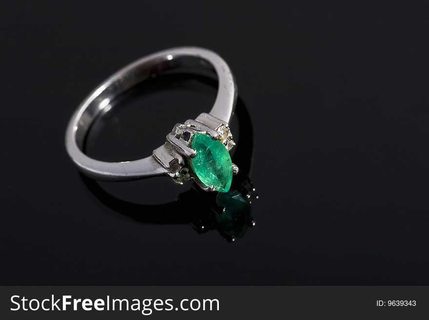 Silver ring with green stone on dark, reflective background. Silver ring with green stone on dark, reflective background