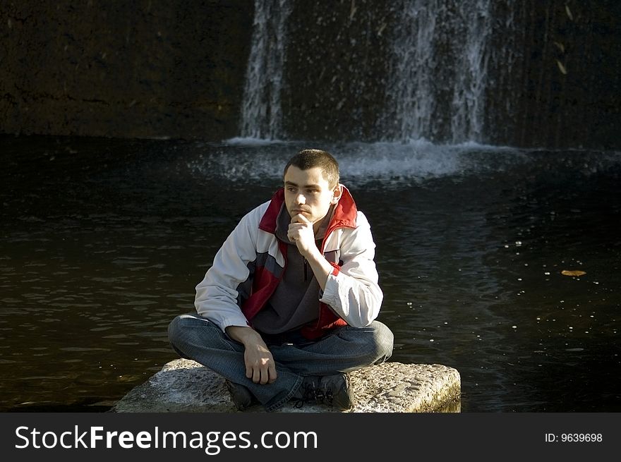 Young man sitting on a stone