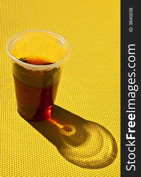 Tea in a plastic glass on a yellow background