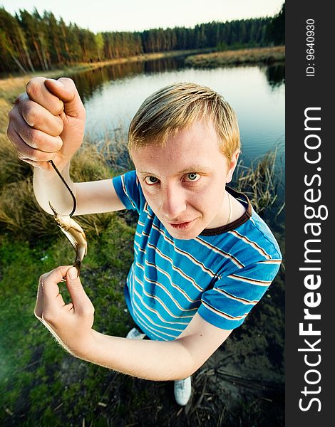 A guy on a river bank demonstrating  his catch. A guy on a river bank demonstrating  his catch