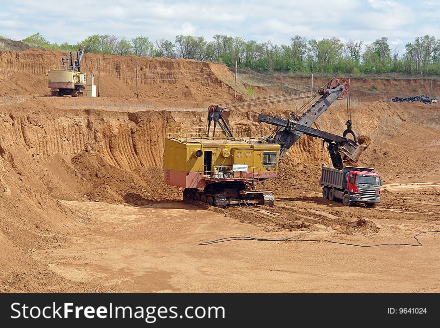 The excavator is loading rock into the truck. The excavator is loading rock into the truck