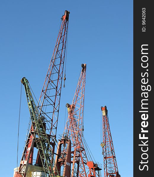 Several cranes in a harbor on blue sky