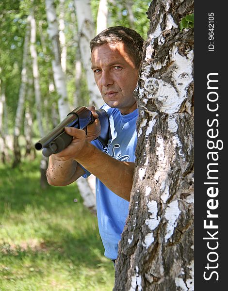 Man with the weapon is hidden behind a tree. Man with the weapon is hidden behind a tree
