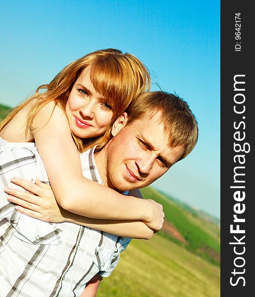 Happy couple outdoor, young man giving his girlfriend piggyback ride