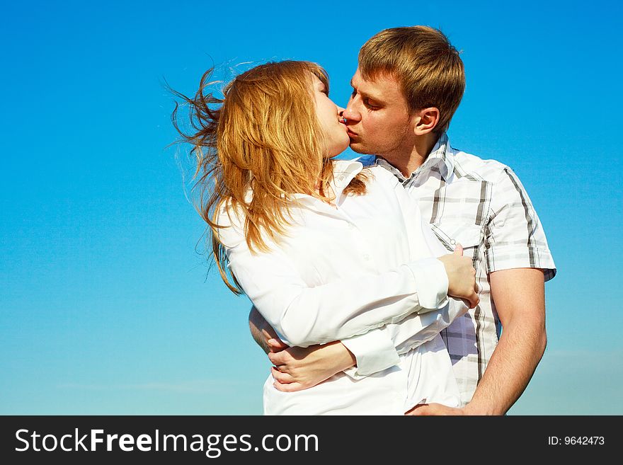 Happy young loving couple kissing outdoor in summertime. Happy young loving couple kissing outdoor in summertime
