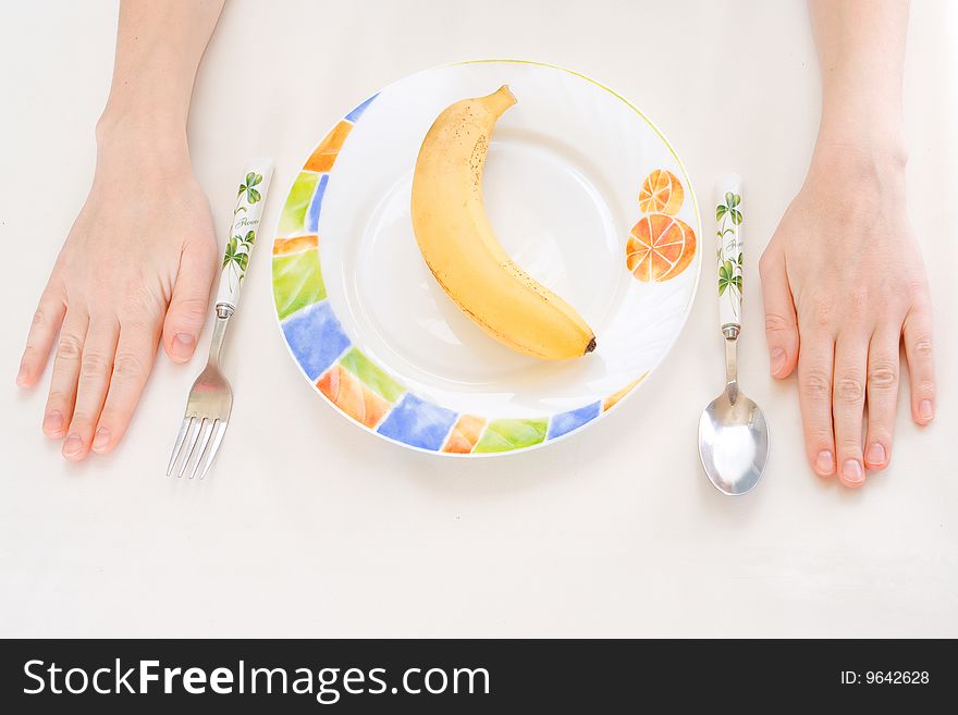 Banana on a plate, fork spoon hands