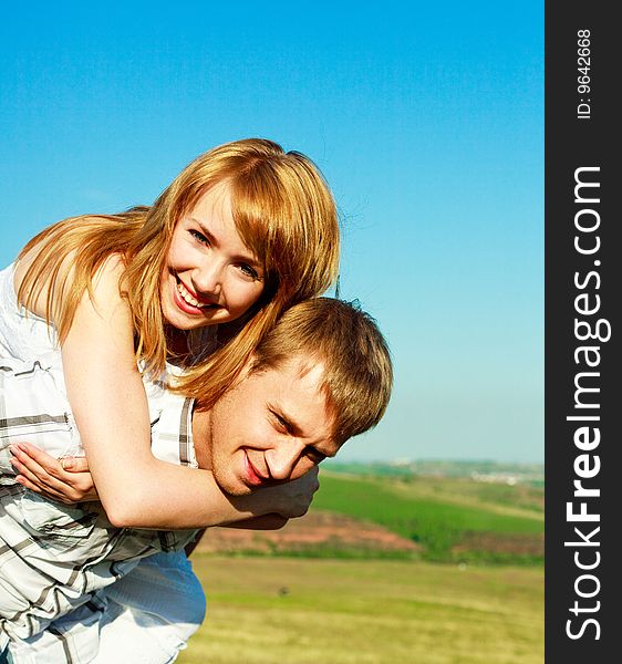 Happy couple outdoor, young man giving his girlfriend piggyback ride