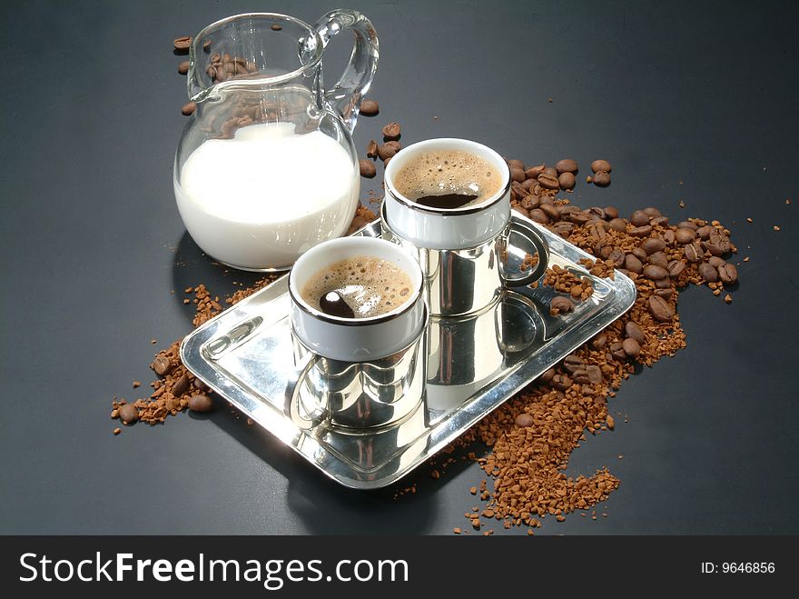 Two cups of coffee, glass of milk, coffee beans and metal plate