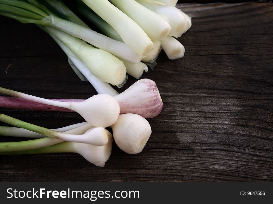 Young onion and garlic on weathering wooden table