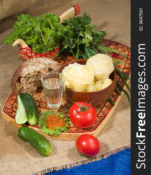 Glass of Russian vodka, tomatoes, greenery, bread and potatoes on canvas. Glass of Russian vodka, tomatoes, greenery, bread and potatoes on canvas