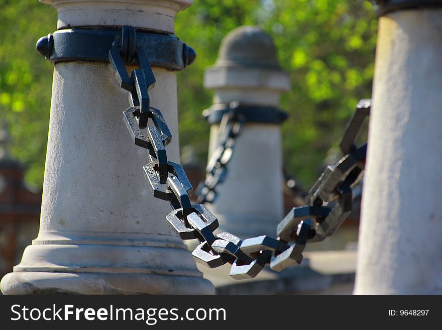 Strong metal chain, detail,  green in bacground, fence