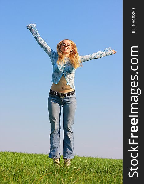 Woman jumping on green grass, blue sky in background. Woman jumping on green grass, blue sky in background