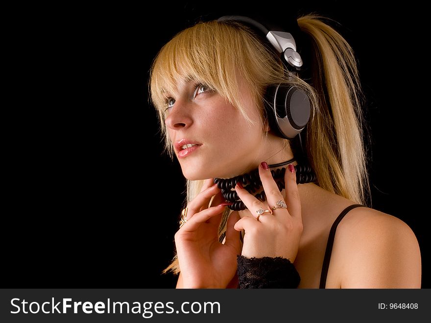Portrait of a young girl with headphones on a black background. Portrait of a young girl with headphones on a black background