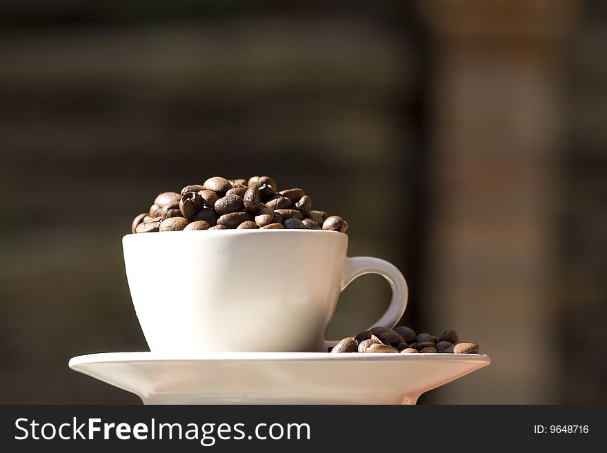 Photo of a coffe cup stacked with whole coffee beans - blur background. Photo of a coffe cup stacked with whole coffee beans - blur background