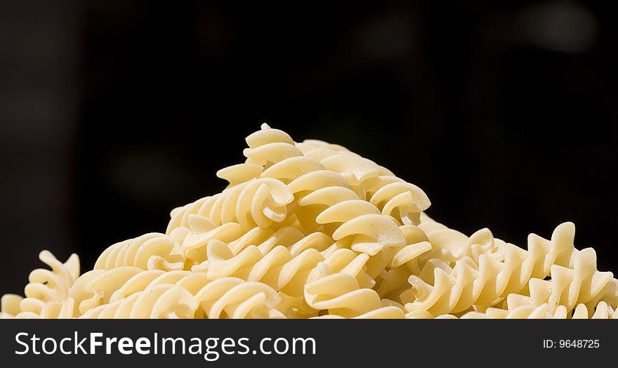 Photo of fusilli (pasta) over a black background