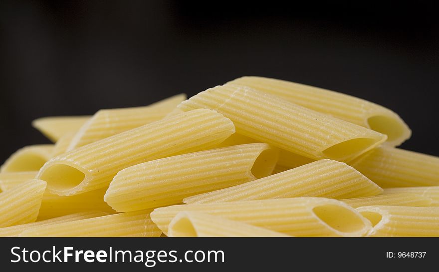 Close up of penne (pasta) over a black background