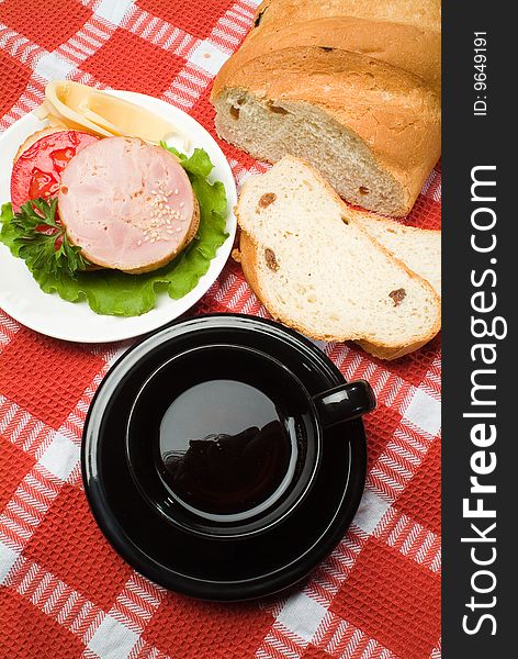 Bread, black cup of tea on a checked tablecloth