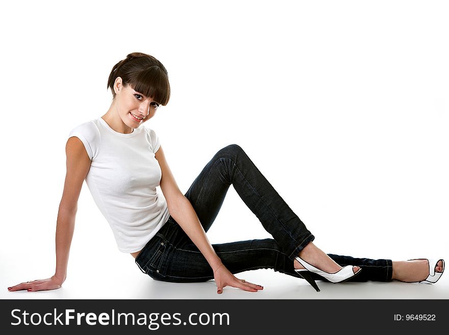 Beautiful young adult girl posing in a studio, isolated on white, sitting on a floor
