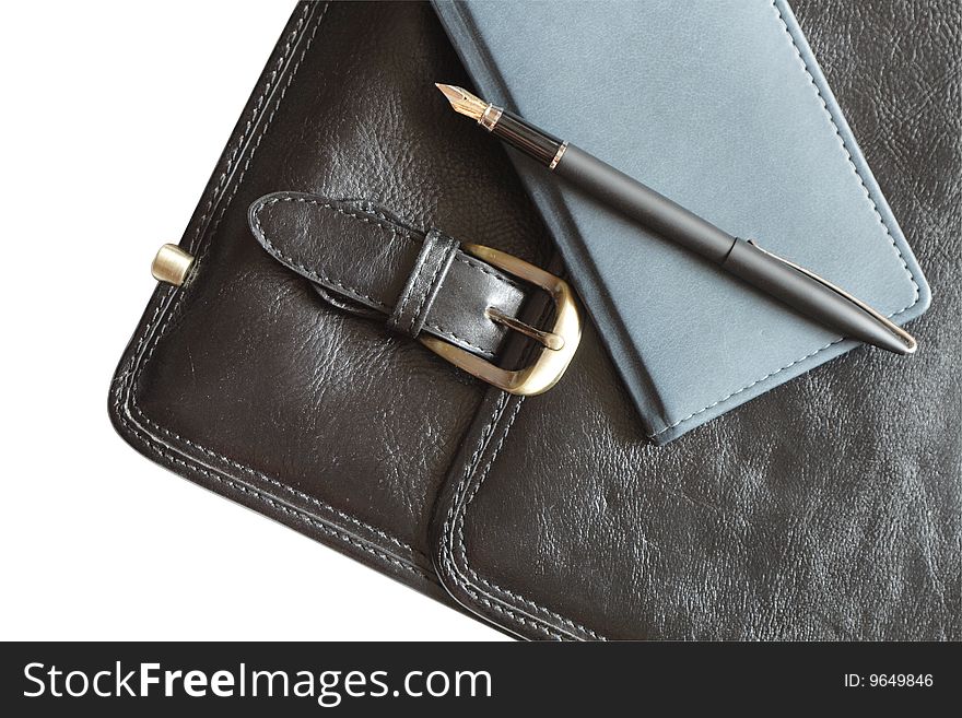 Pen and notebook lying on black leather brief case. Isolated with clipping path. Pen and notebook lying on black leather brief case. Isolated with clipping path