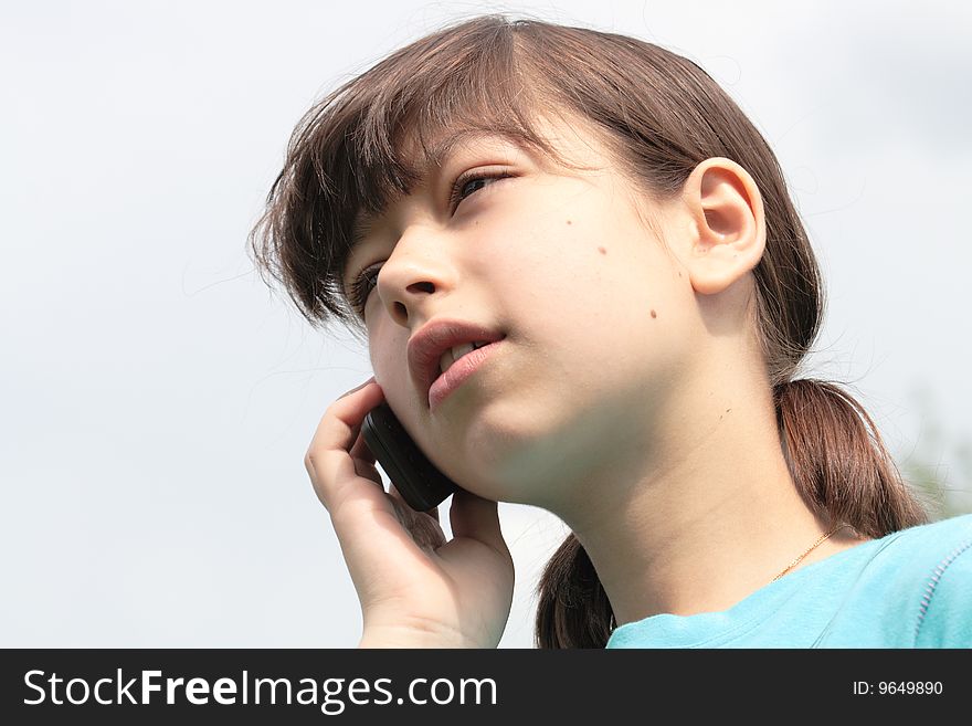 Close-up of nice young girl with mobile phone isolated on sky background. Close-up of nice young girl with mobile phone isolated on sky background