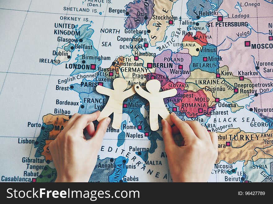 Hands holding wooden little men on map background. Symbol of friendship, partnership or cooperation between countries