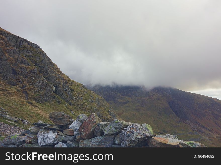 Gray and Brown Rocks Green Lush Mountains and White Clouds in Background