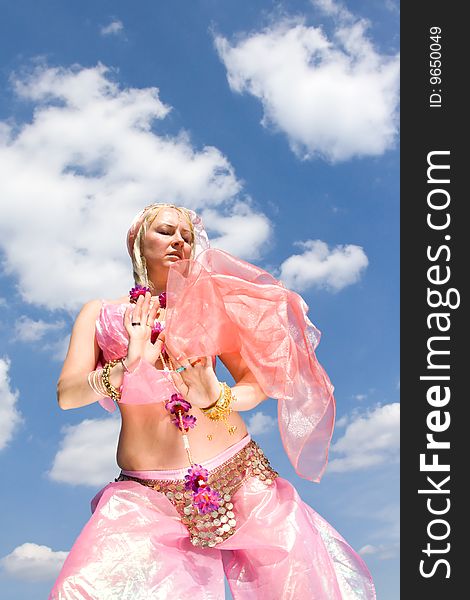 A woman in pink asian dress dancing and a blue sky. A woman in pink asian dress dancing and a blue sky