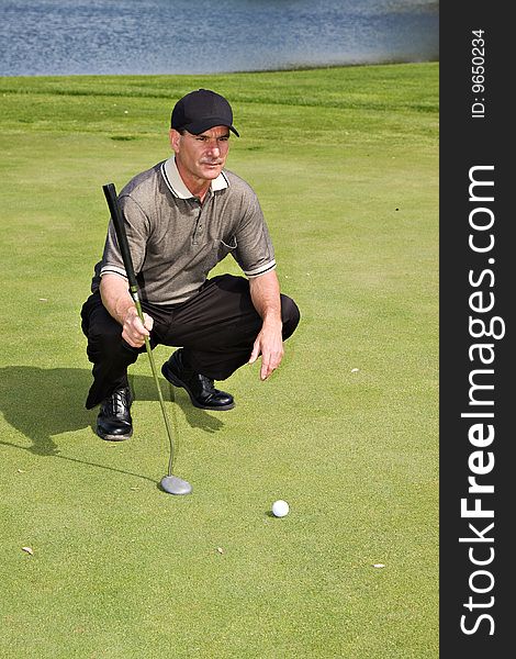 A well-dressed male golfer sizing up his next putt. A well-dressed male golfer sizing up his next putt.
