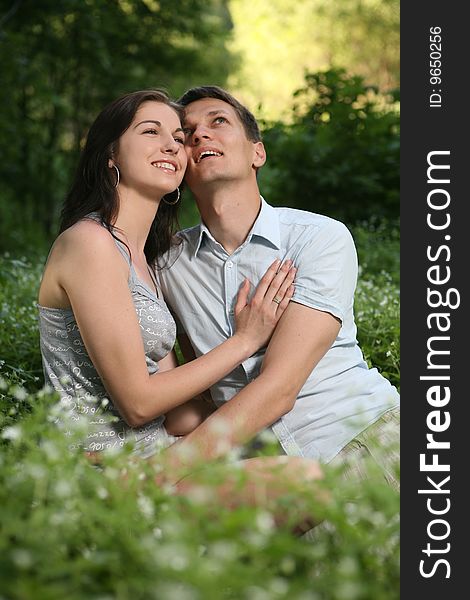 Man and woman sitting on the grass. Looking up. Man and woman sitting on the grass. Looking up