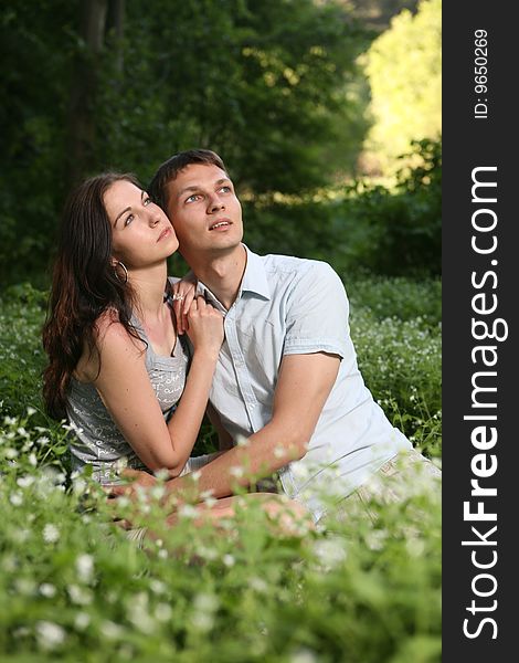 Man and woman sitting on the grass. Looking up. Man and woman sitting on the grass. Looking up
