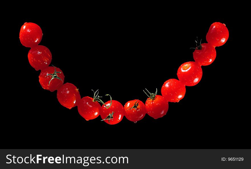 Smile of cherry tomatoes on black background