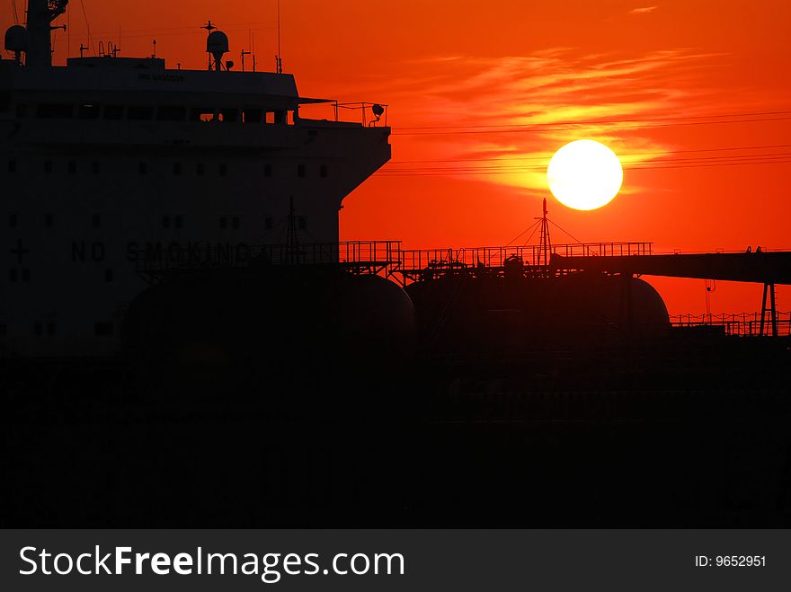 The silhouette of a tanker against an orange sunset sky. The silhouette of a tanker against an orange sunset sky.