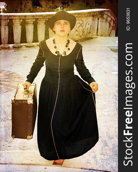 A beauitful girl is staring,looking in front.she wears a black dress and holds an old luggage. A beauitful girl is staring,looking in front.she wears a black dress and holds an old luggage