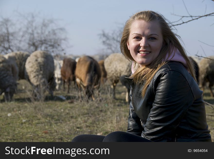 A girl sits on a stone on a background the herd of