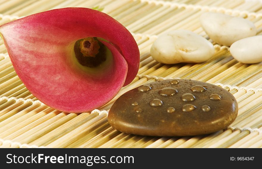 Pink calla blossom with stones on a bast mat