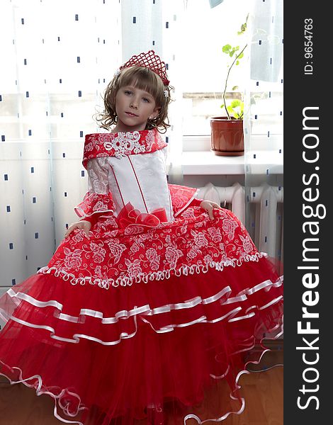 A little girl in red dress at home