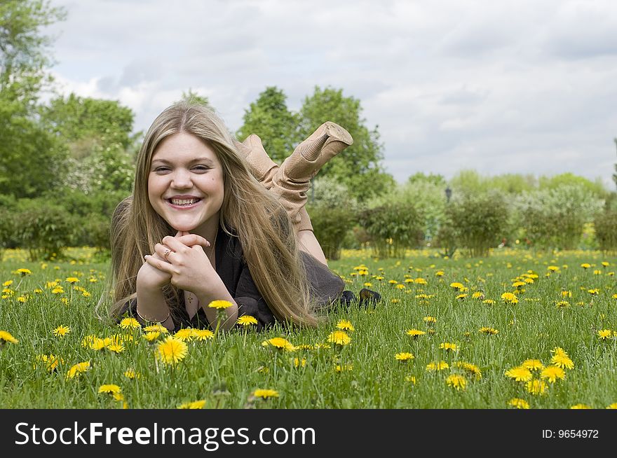 Young adult beautiful girl lying on the grass and smiling. Young adult beautiful girl lying on the grass and smiling