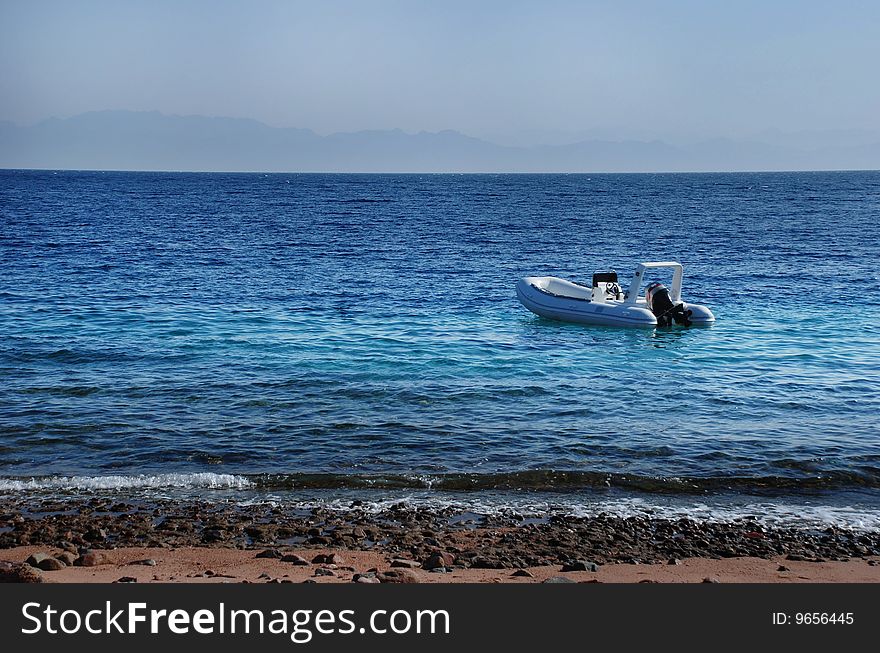 A motor rubber divers boar with nobody inside over coral reef going along shore in Dahab, Egypt. A motor rubber divers boar with nobody inside over coral reef going along shore in Dahab, Egypt