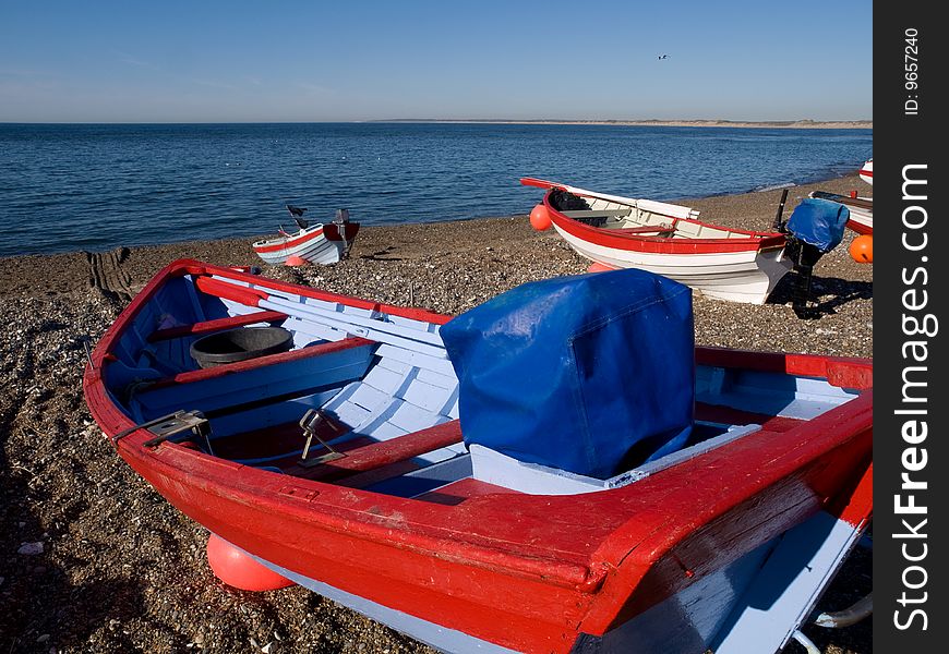Fishing Boats dragged on land with blue sky and ocean view.